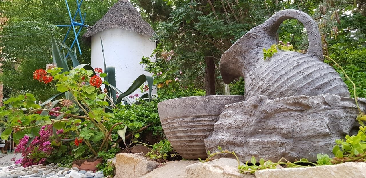 Clay amphorae among red and pink flowers in the garden