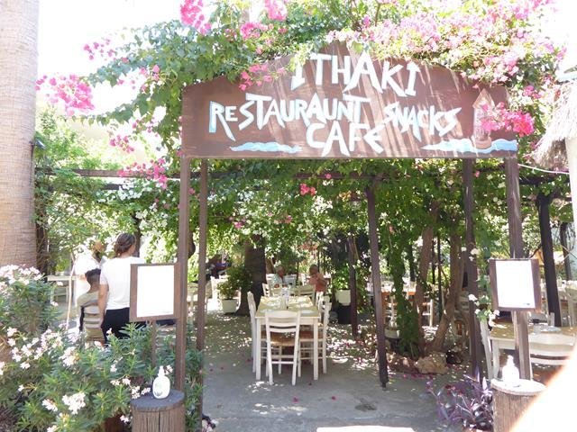 The hand-painted Ithaki sign framed in bougainvillea